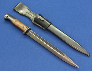 A WW2 Portuguese Model M937 German made Bayonet. Pommel and scabbard with Waffenambt stamp WaA519. Pommel with number C13286, scabbard marked 89H. Length 40,5cm. In near mint condition. Price 325 euro
